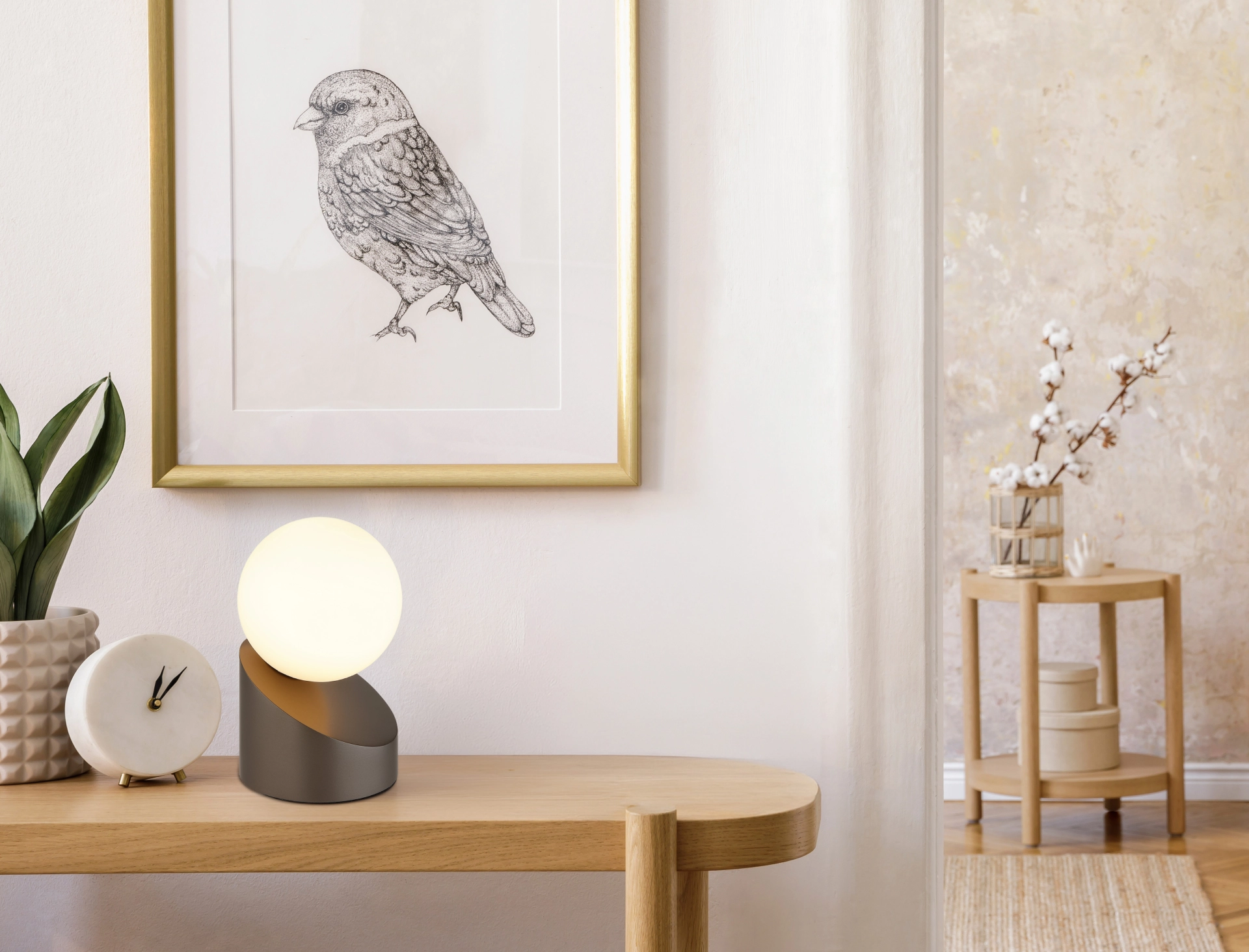 Tischleuchte ALISA von Globo Handels GmbH: kaffeefarbenes Metall mit abgeschrägtem Sockel und opaler Glaskugel, warmes 3000 K Licht, Touch On/Off, G9 LED 3,5 W – dekorativ auf Holztisch neben Uhr und Vogelzeichnung.
