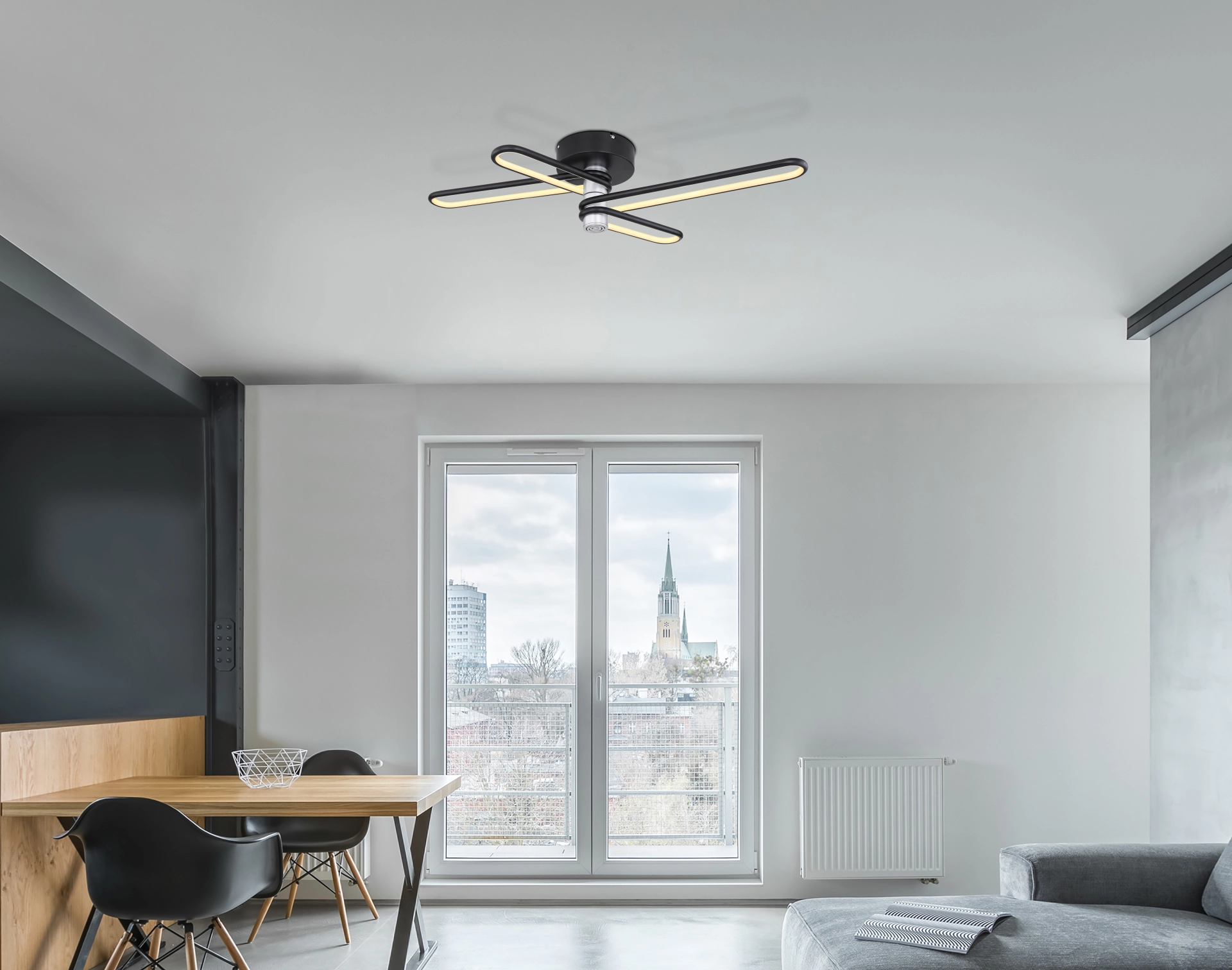 Moderne Deckenlampe TOPPOLE von Globo Handels GmbH (58007DL), 91,5x46,5 cm, schwarz-mattes Aluminium mit opalem Kunststoff; vier L-förmige Aluröhren um 5W Bluetooth-Lautsprecher, warmweiß 3000 K, 1400 lm – im Wohnraum montiert.